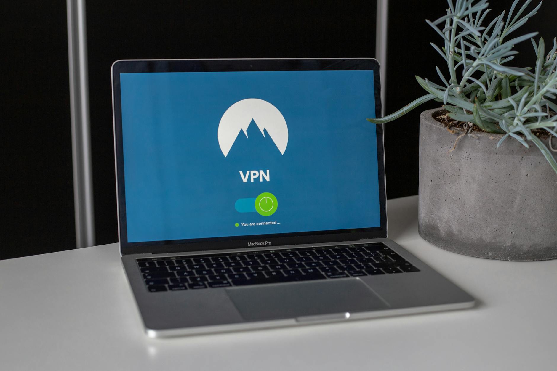 Laptop z uruchomioną aplikacją VPN na biurku obok małej rośliny