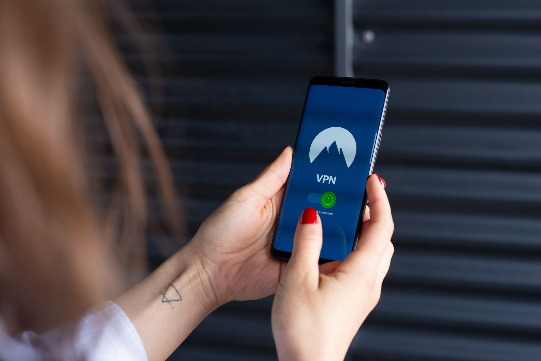 Kobiece dłonie konfigurujące aplikację VPN na smartfonie dla bezpieczeństwa