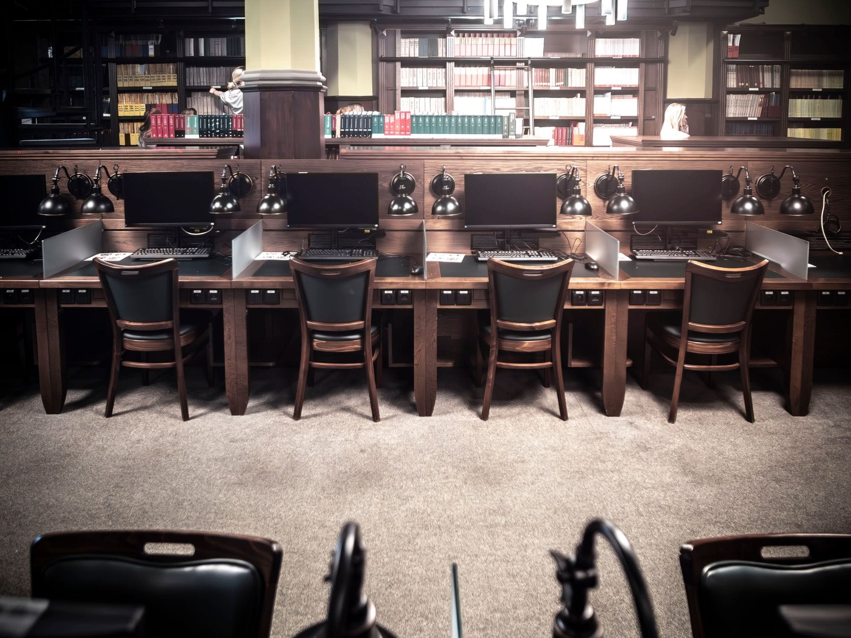 Puste stanowiska komputerowe w bibliotece z lampami retro